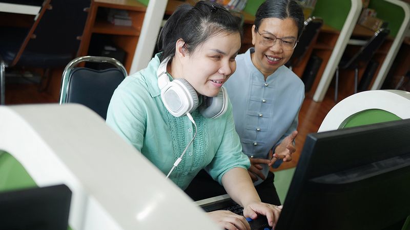 Photo of a blind student using technology alongside an adult